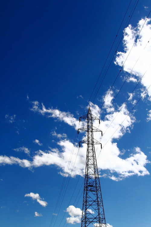 白い雲と夏の青空を背景にそびえる送電鉄塔