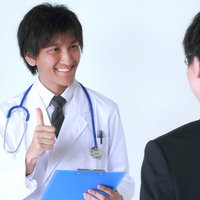 笑顔でサラリーマンに診断結果を説明する医者の写真