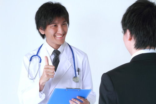 笑顔でサラリーマンに診断結果を説明する医者