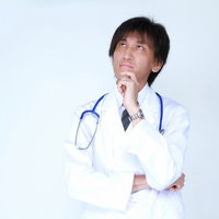 天井を見上げて何かを考えている白衣のドクターの写真