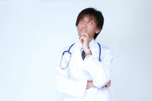 天井を見上げて何かを考えている白衣のドクター