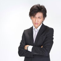 水色の壁の前で腕を組んで立つスーツ姿のビジネスマンの写真