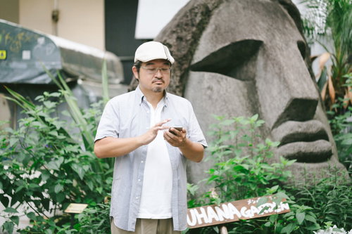 渋谷モヤイ像の前でスマホを操作する眼鏡をかけた男性