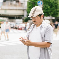 街中で横断中にスマートフォンを操作する男性の写真