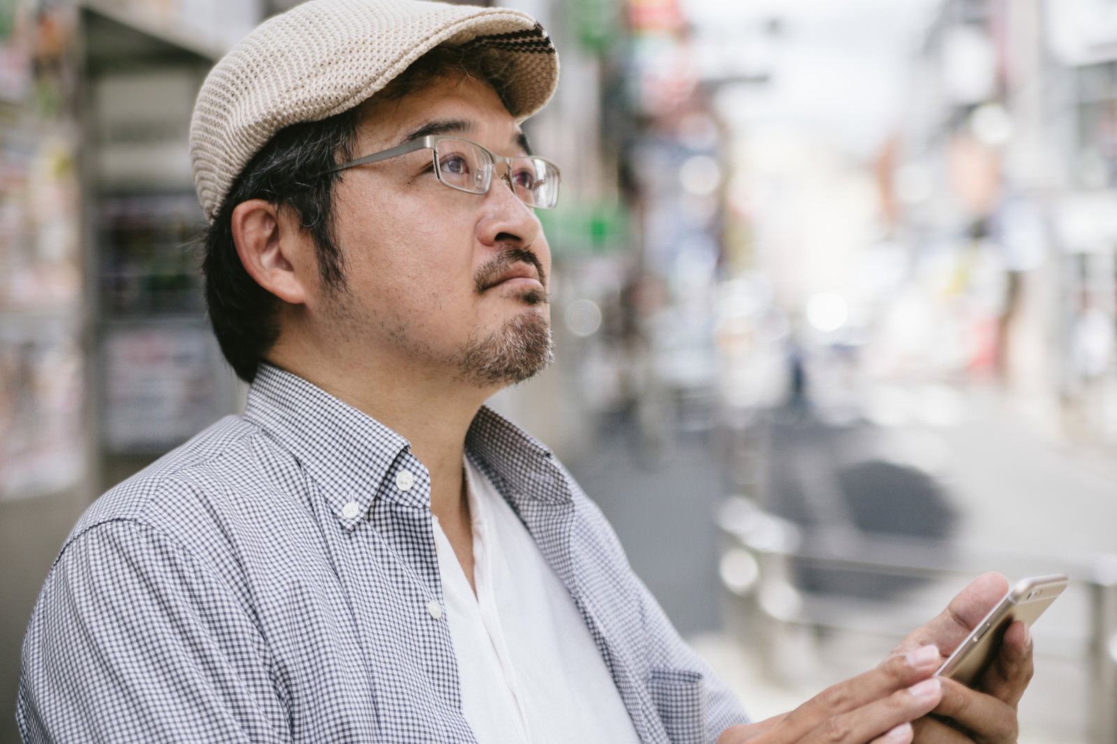 マップアプリを片手に困惑して上を見上げる男性［モデル：ナリシゲ］