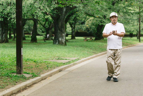 公園内でスマートフォンを片手に探索する男性