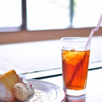 窓際のケーキセットとアイスティーの写真