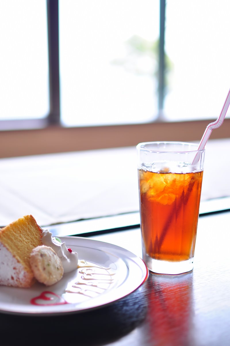 窓際のテーブルに並ぶケーキセットとアイスティー