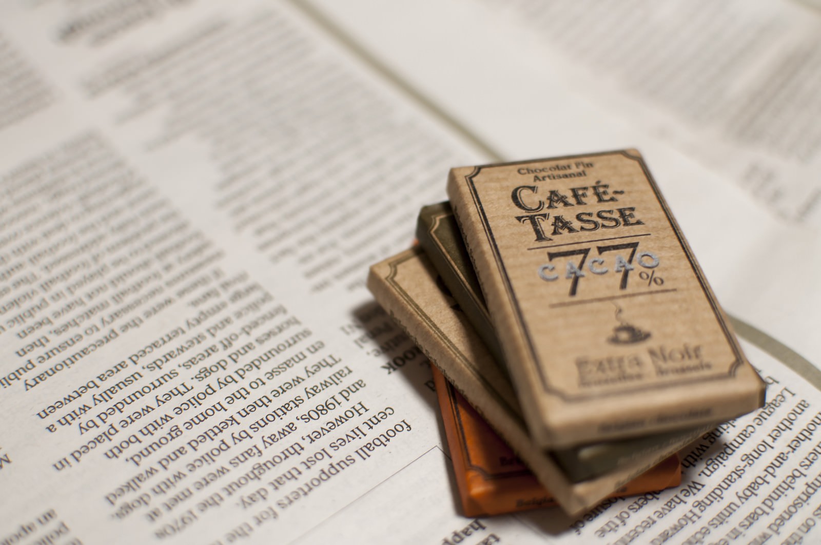 開いた本の上にカフェタッセのダークチョコレートが3個積み重ねられている