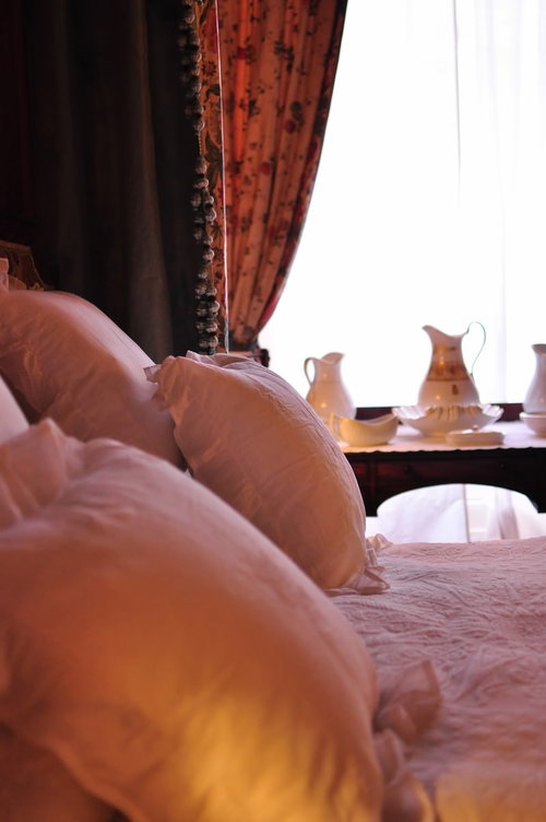 白いシーツと枕が整えられたマナーハウスのベッド