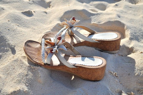 砂浜に置かれた花飾り付きサンダル