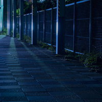 照明が照らす工場沿いの夜道の写真