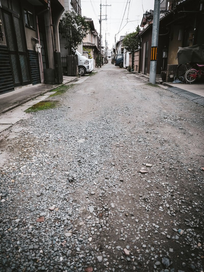住宅街の路地裏に続く砂利道と民家
