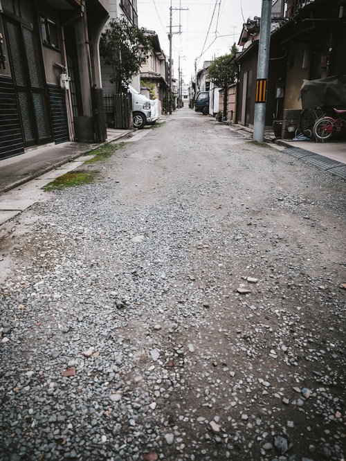 住宅街の路地裏にある砂利道と民家の街並み