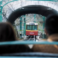 石造りトンネル越しに接近する赤と白のケーブルカーの写真
