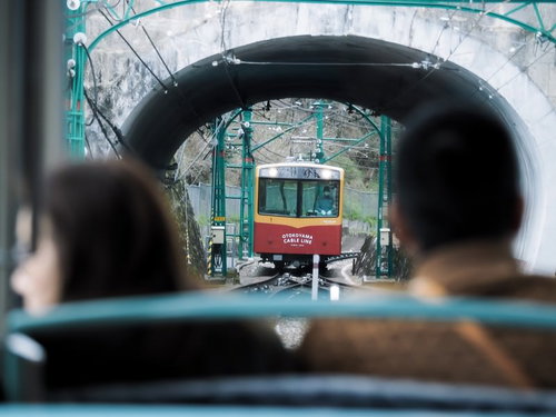石造りトンネル越しに接近する赤と白のケーブルカー