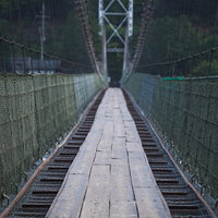 早朝の谷瀬の吊り橋を向こう岸へ続く木製の板張りの道の写真