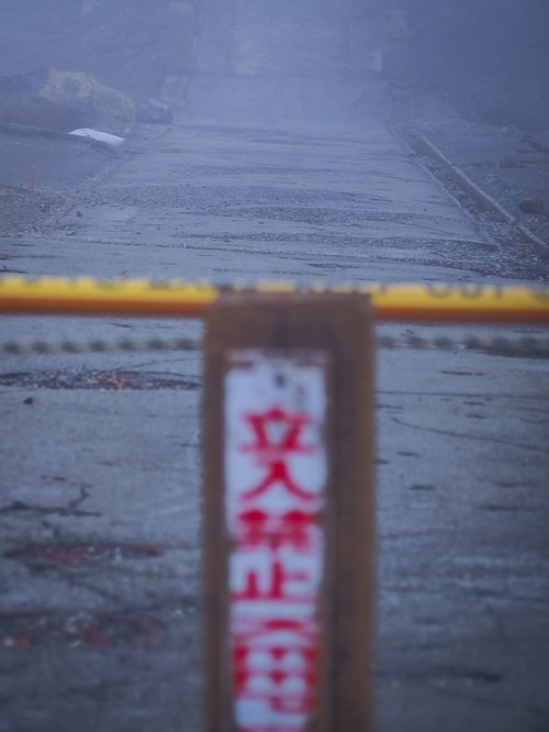 崩壊した道路に設置された立入禁止の札と危険区域