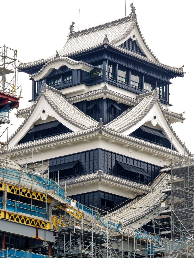 工事用足場に囲まれた修復工事中の日本の城の天守閣