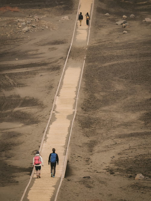 阿蘇山の草千里に敷かれた木道を歩く登山者達