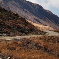 阿蘇山の荒れ果てた山へと続く道路と険しい岩肌の写真