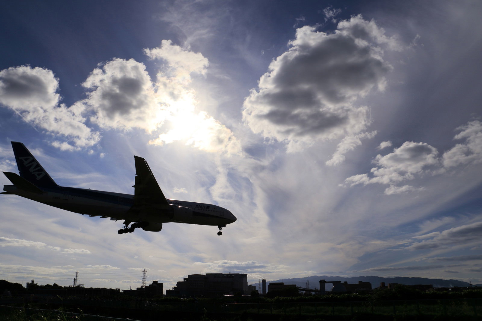 逆光でシルエットになる着陸態勢の旅客機
