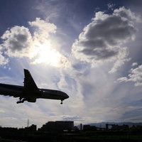 秋澄む中への着陸体勢の旅客機が逆光でシルエットを描くの写真