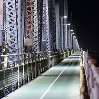夜間に照明が灯る鋼鉄製の陸橋と街灯の写真