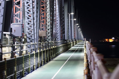 夜間に照明が灯る鋼鉄製の陸橋と街灯