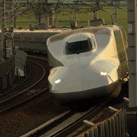 夕日を背に受けて線路を走るN700系X67新幹線の写真