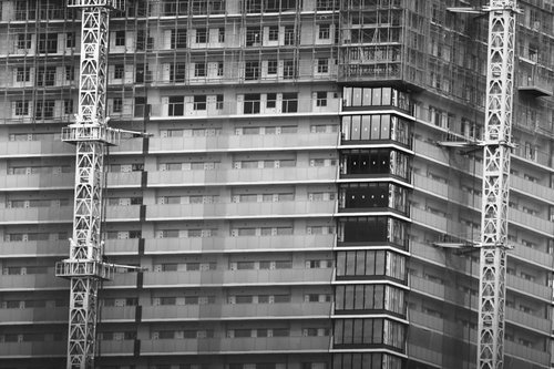 建設中の高層マンションと複数の白いクレーン機の工事現場