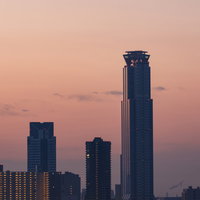 朝日と夕焼けに映るコスモタワーと大阪のビル群の写真