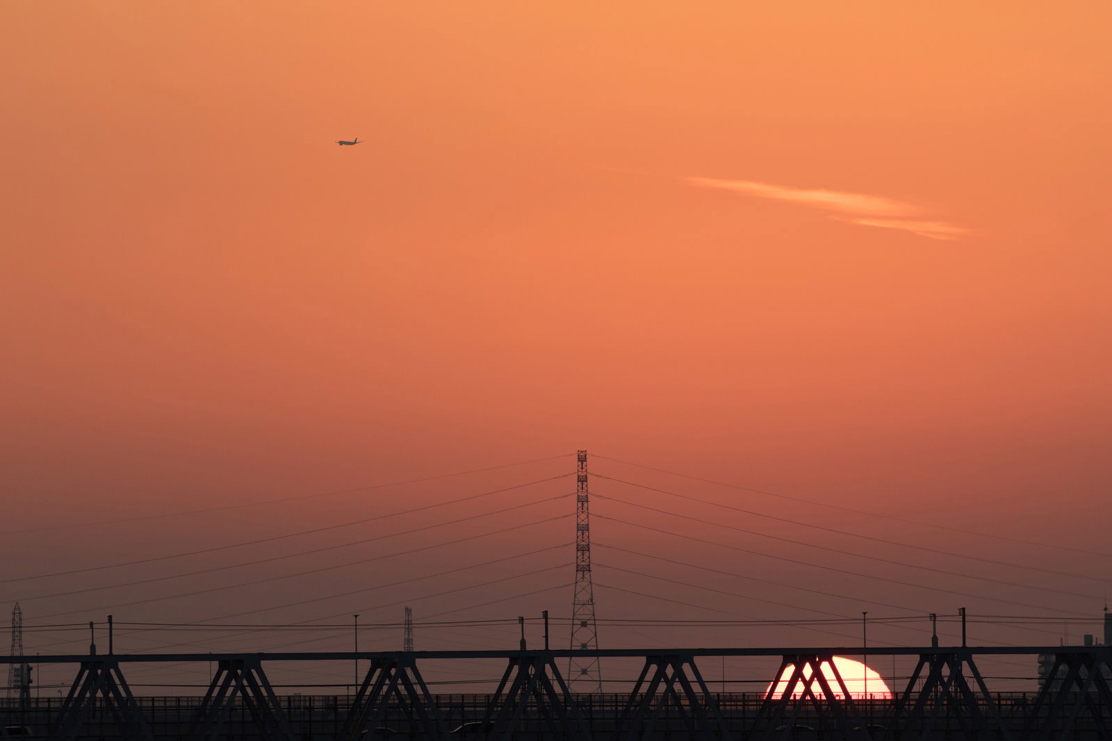 夕日を背景にシルエットで映る鉄橋と鉄塔