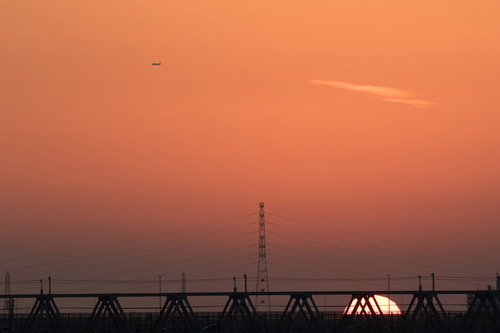 暮れなずむ夕日に照らされる鉄橋と鉄塔のシルエット