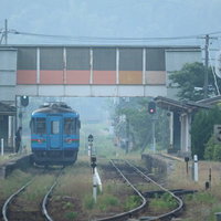 地方のローカル線と長閑な風景の中を走る青い電車の一コマの写真