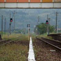 田舎のホームと赤信号が点灯する線路と踏切の写真