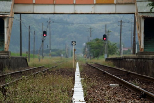 田舎のホームと赤信号が点灯する線路と踏切