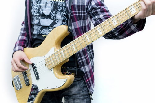 スタジオの暗い照明の中でベースギターを弾く手元の接写