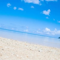 青く透き通った水面から珊瑚と砂が見える沖縄の海の写真