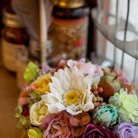 赤やピンクの造花をバランスよくまとめたフラワーアレンジメントの写真