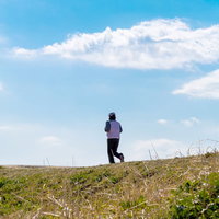 夕方の河川敷をジョギングするランナーの横姿の写真