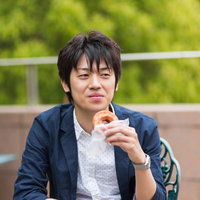 カフェのテーブルでドーナツを手に取って食べる男性の写真