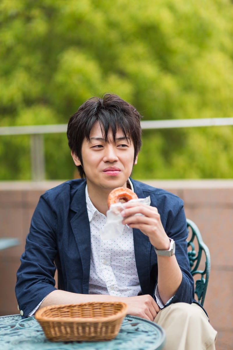 テーブルでドーナツを食べる男性［モデル：Tsuyoshi.］