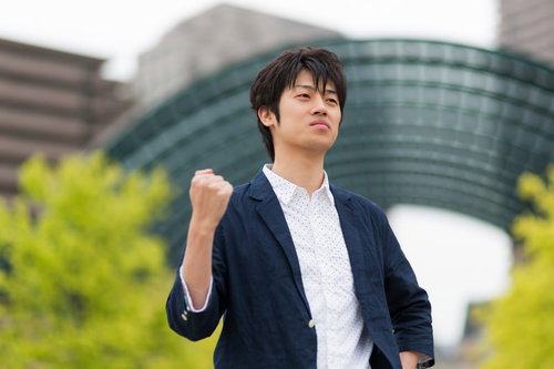 デスクの前でガッツポーズを決めるWebデザイナー