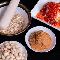 小皿に分けて盛られたゴマ・味噌・豆・キムチの調味料と食材の写真