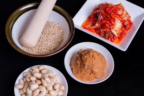 小皿に分けて盛られたゴマ・味噌・豆・キムチの調味料と食材