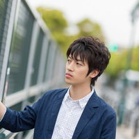 金網のフェンスを両手で握りしめてこちらを見る青年の写真