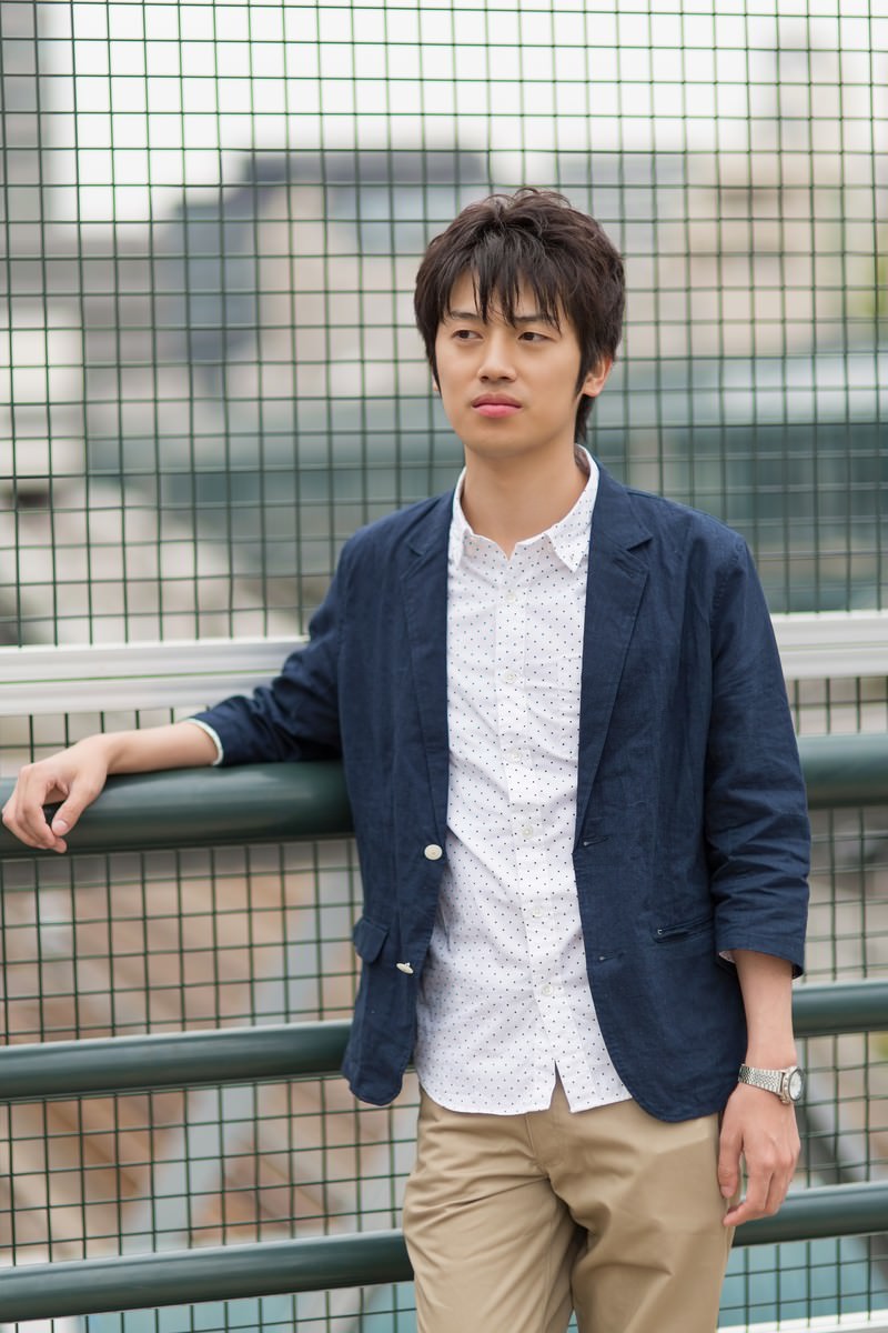 金網に寄りかかる腕組みの男性［モデル：Tsuyoshi.］
