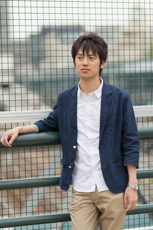 金網フェンスに寄りかかって腕を組みポーズする男性