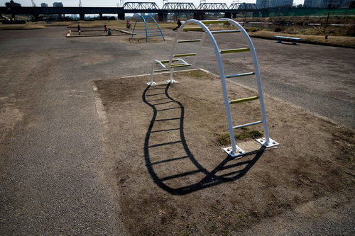 芝生とベンチが並ぶ河川敷の静かな公園の風景